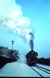 Der Interzonenzug von Hamburg nach Dresden fährt im verschneiten Bahnhof Büchen mit gewaltiger Dampfwolke an